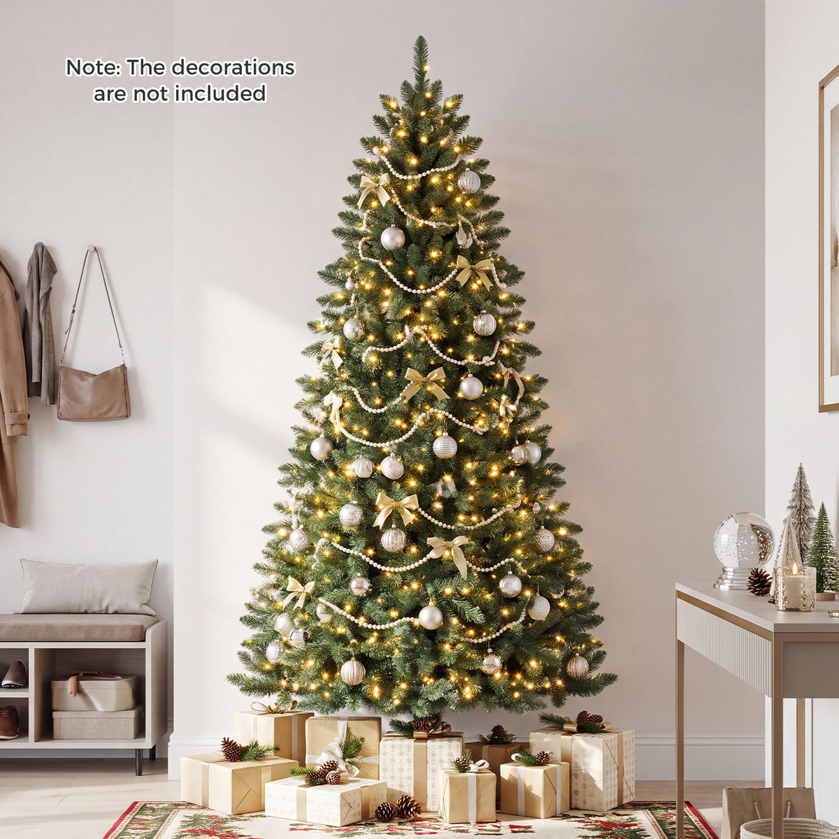 Lit Christmas tree decorated with pale ornaments and garlands, surrounded by gifts in a bright room.