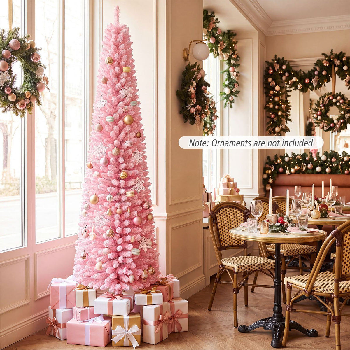 Decorated pink snow-flocked Christmas tree beside wrapped gifts in a bright dining room