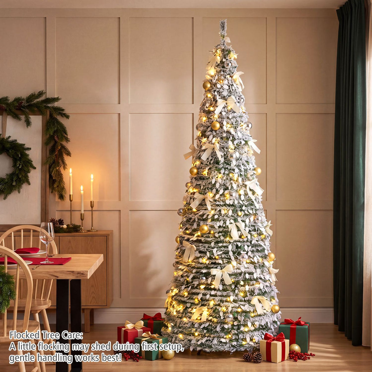 Snow-flocked tree decorated with warm lights, gold and silver ornaments, and white bows in a dining room.