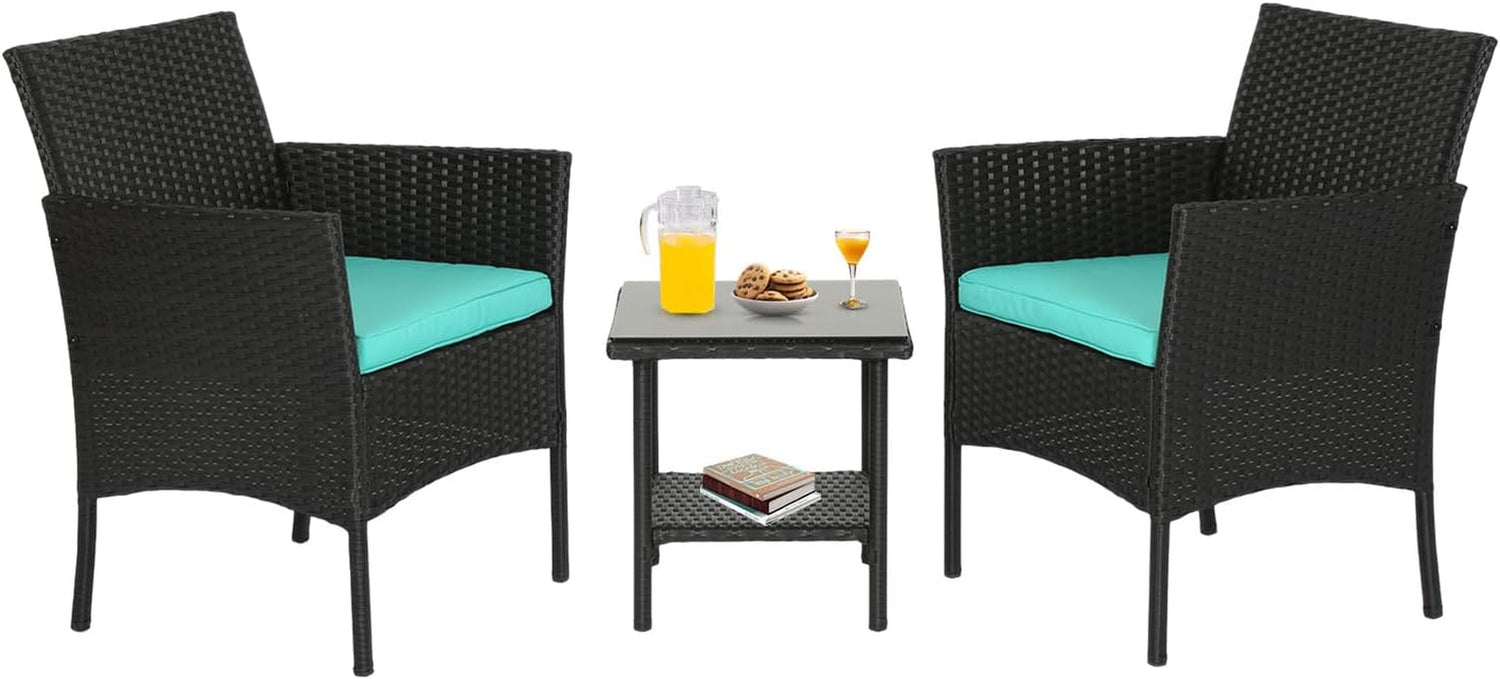 Two black woven rattan armchairs with turquoise seat cushions flanking a small square glass-top side table with drinks.