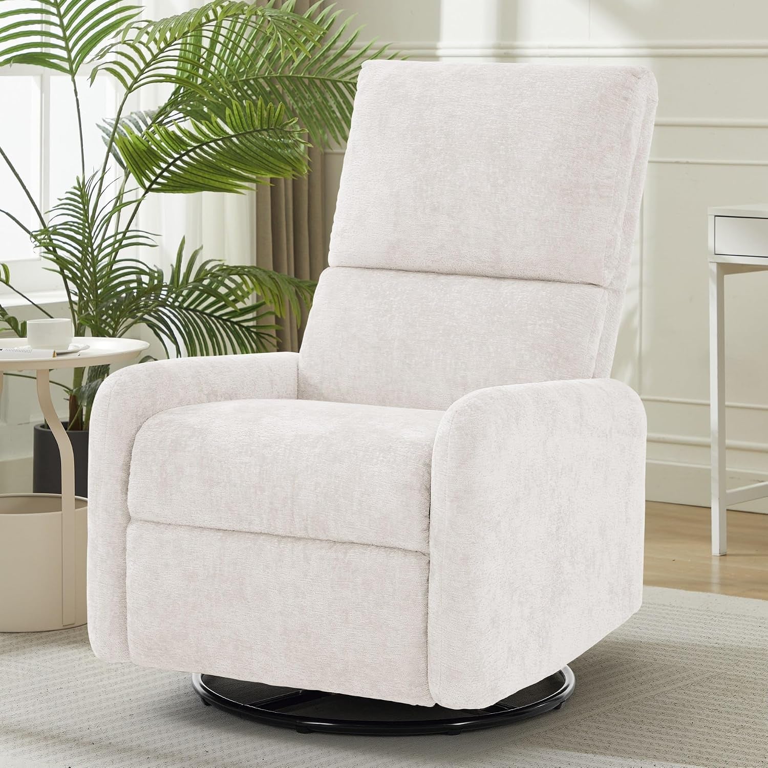 Pale cream swivel glider chair positioned near a side table and tall plant, viewed slightly left-front.