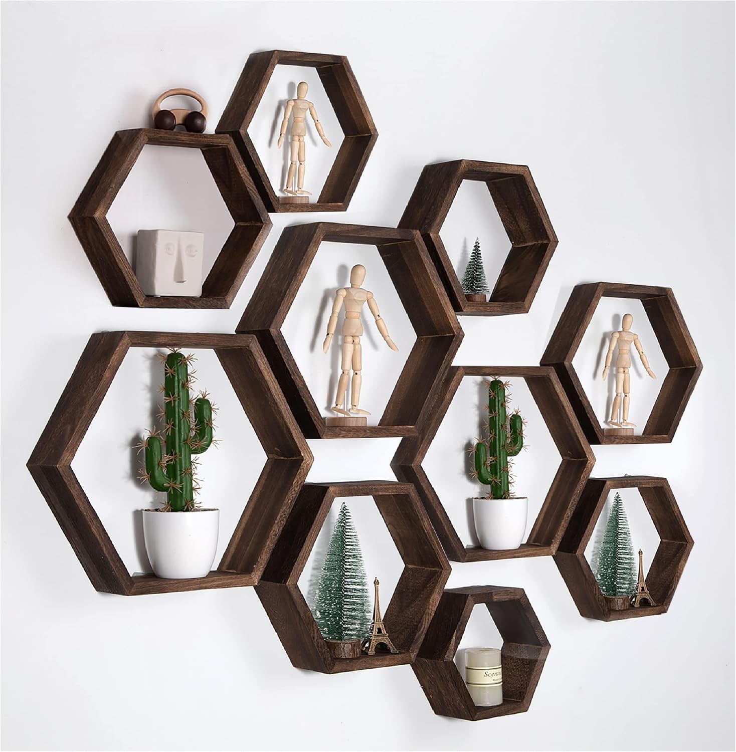 Arrangement of dark brown hexagon shelves on a white wall displaying cacti, mini trees, and mannequins.