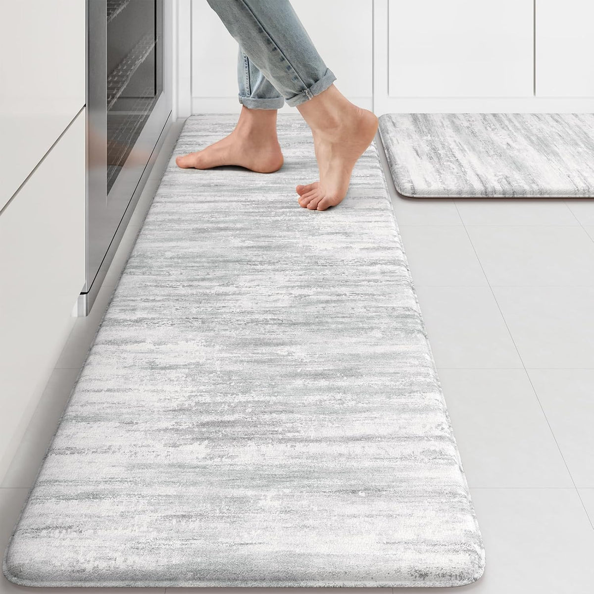 Light gray marbled kitchen runner with a person standing barefoot near an oven, second mat visible.