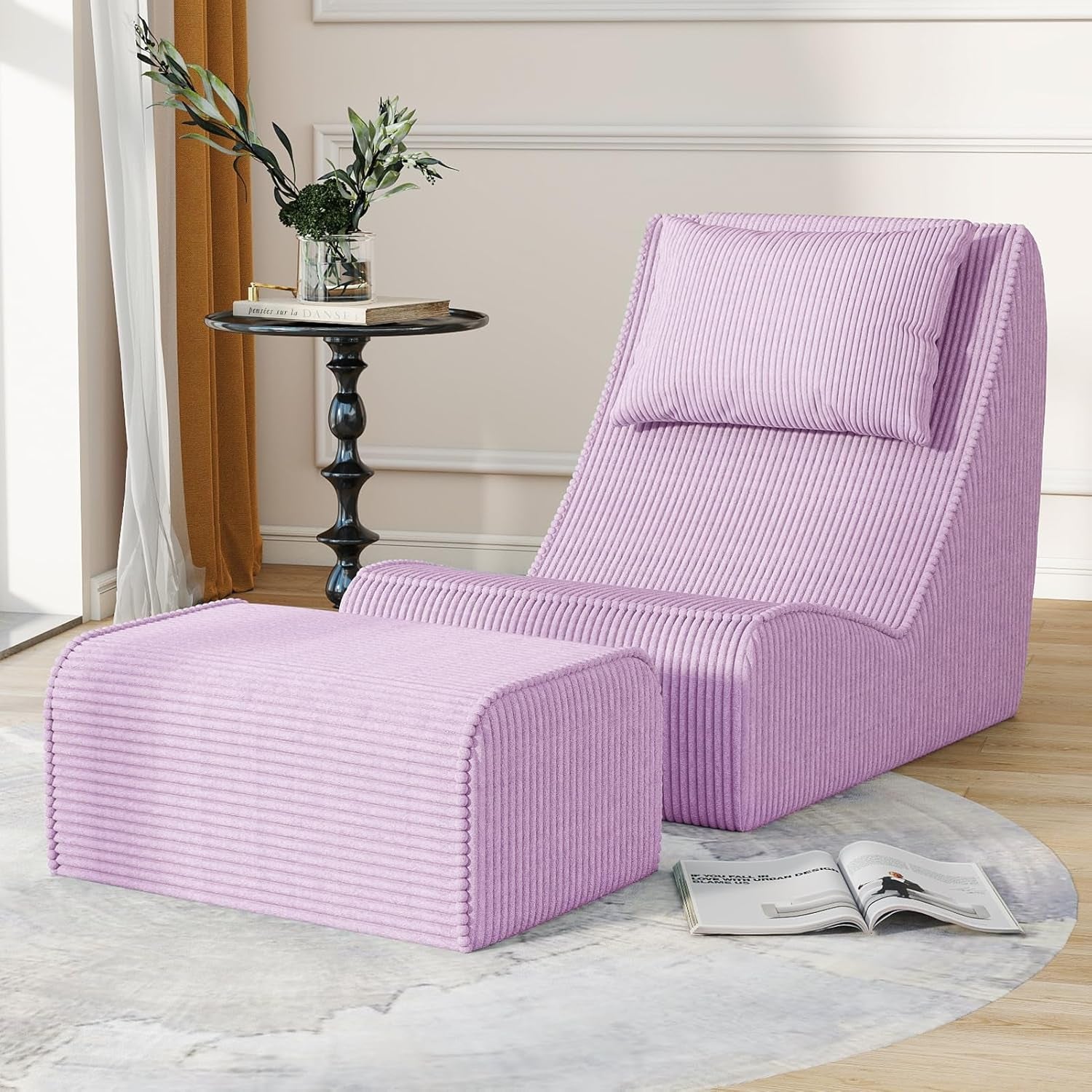 Lavender-pink chaise lounge and ottoman positioned on a round rug with a decorative plant and book nearby.