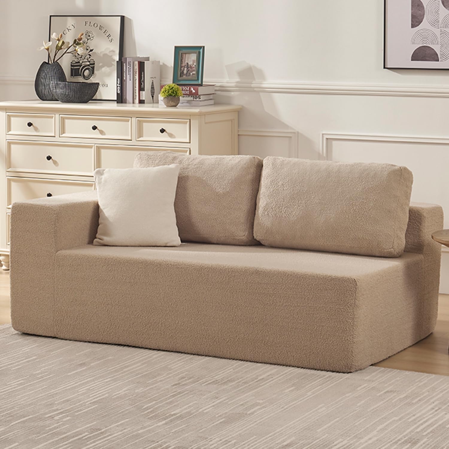Beige two-seat modular sofa section with back cushions and a white throw pillow beside a dresser.