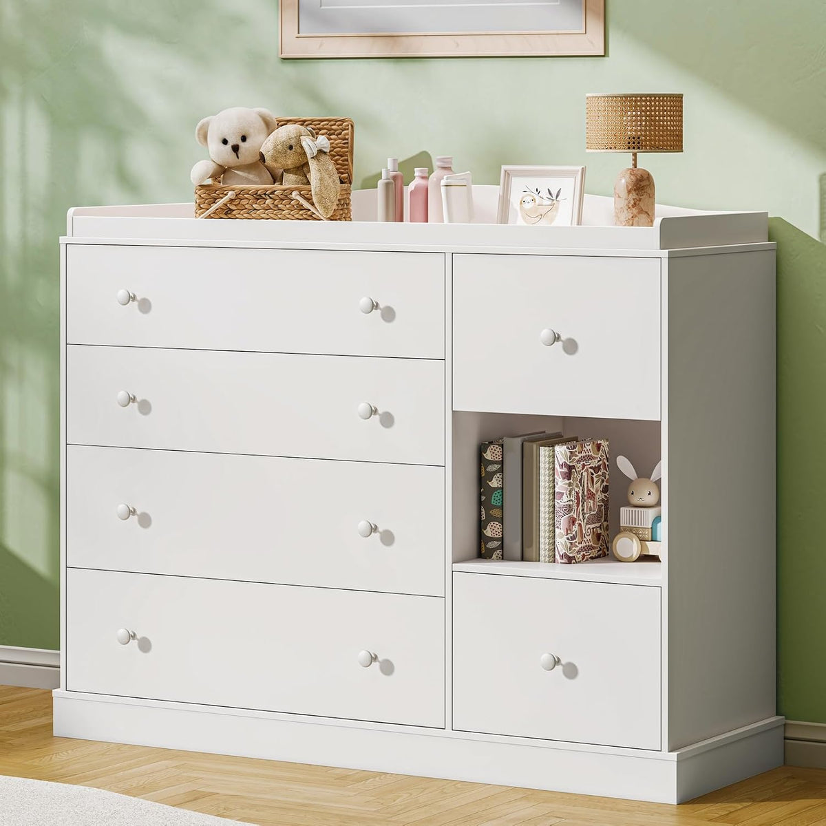 Front-right view of a white six-drawer dresser with a top changing tray and open cubby filled with books and toys.