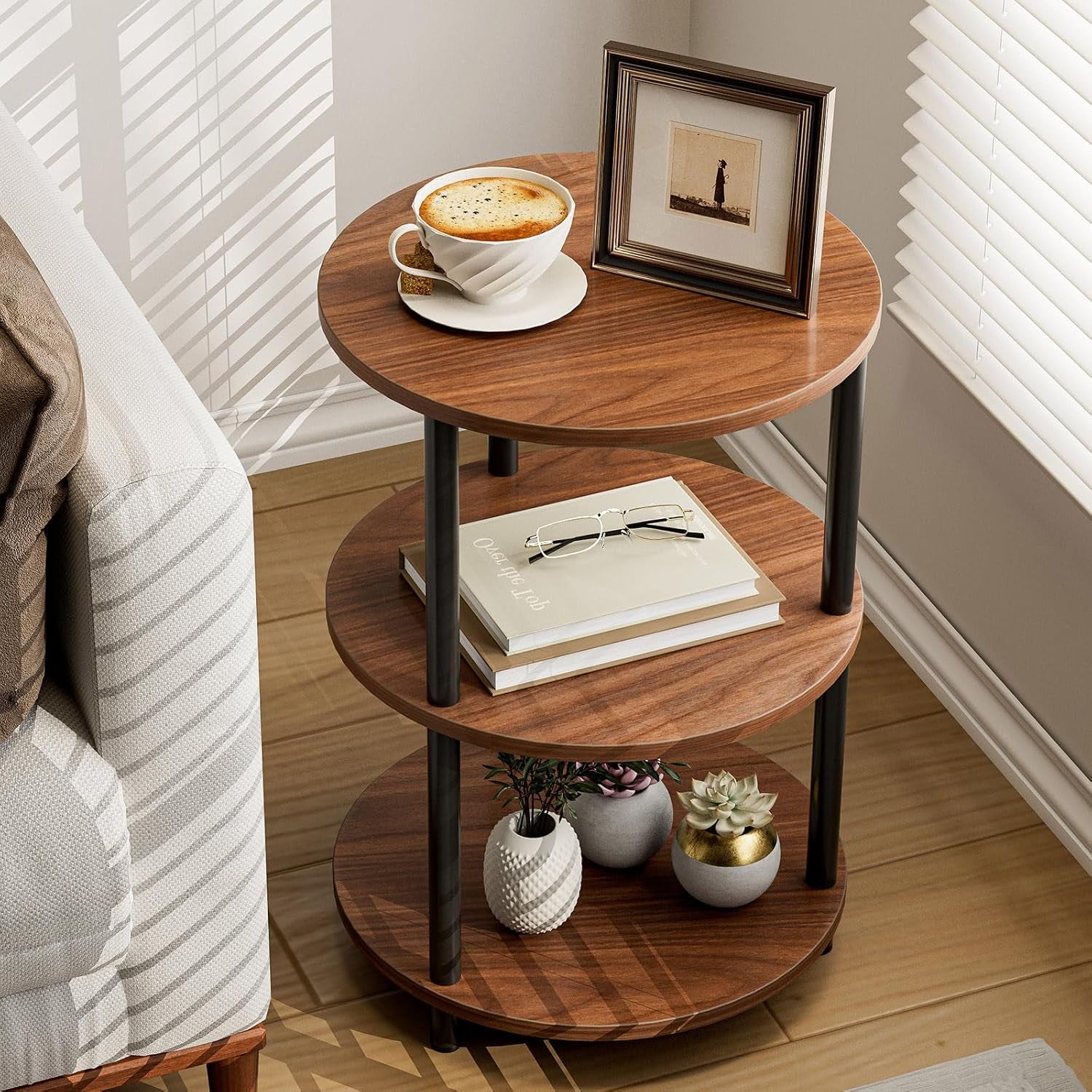 Three-tier round side table in rustic brown beside a sofa holding a cup, books and small plants