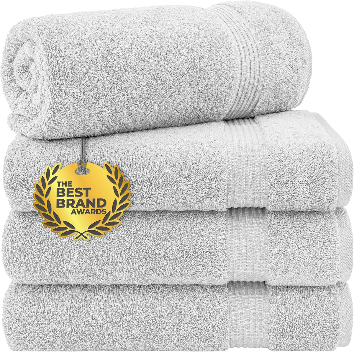 Three neatly stacked white towels with a rolled towel on top and a gold award medallion tag