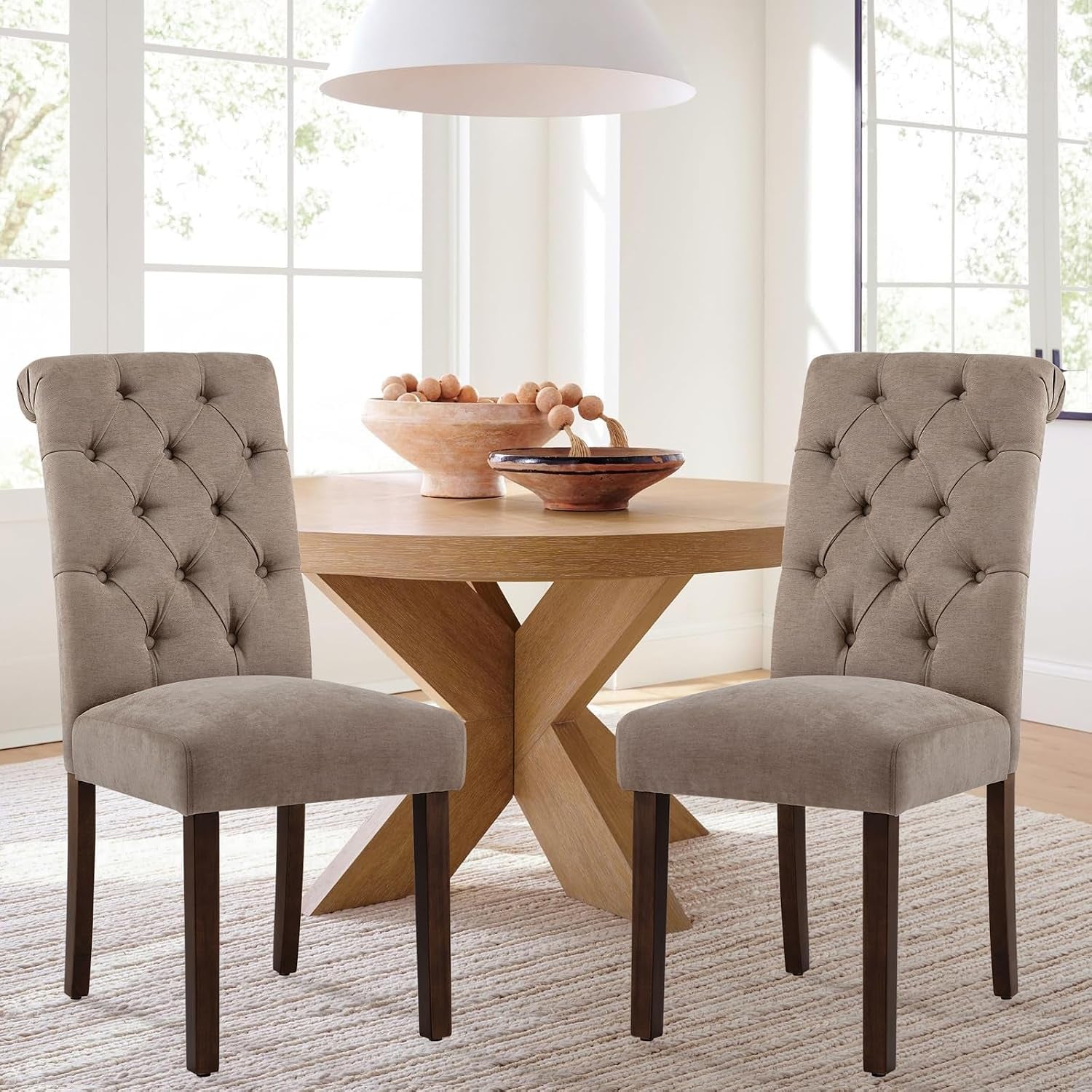 Two taupe Parsons dining chairs paired at a light wood table in a sunlit dining nook