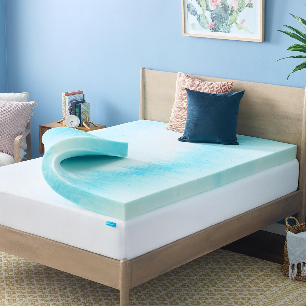 Bedroom scene with a teal marbled foam mattress topper partially rolled back on a wood bed with decorative pillows.