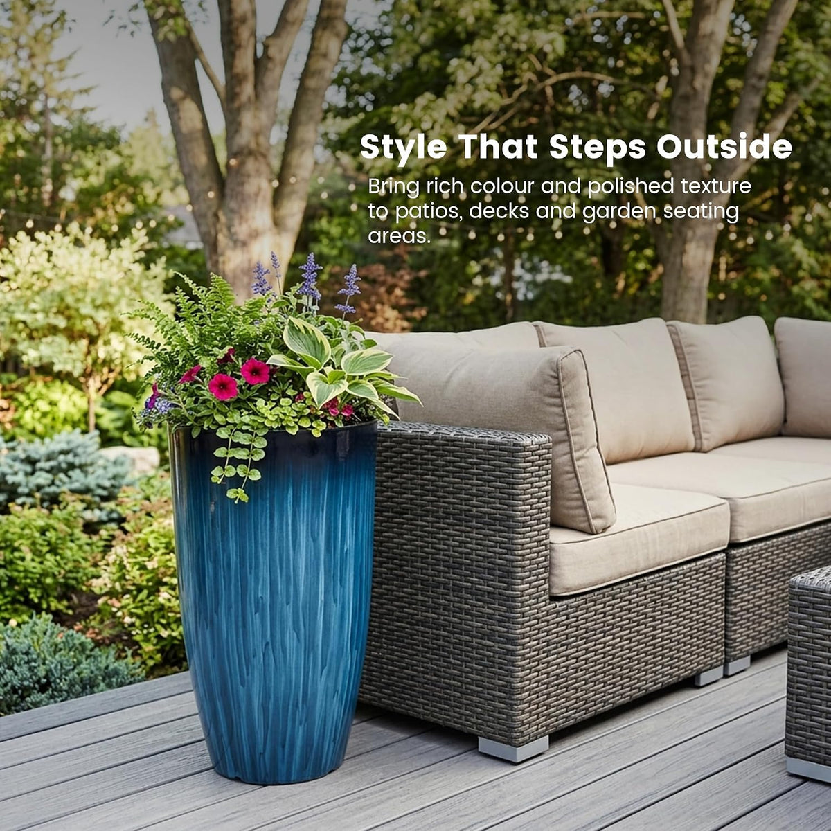 Blue gradient planter on a deck beside a wicker sectional filled with mixed flowering plants