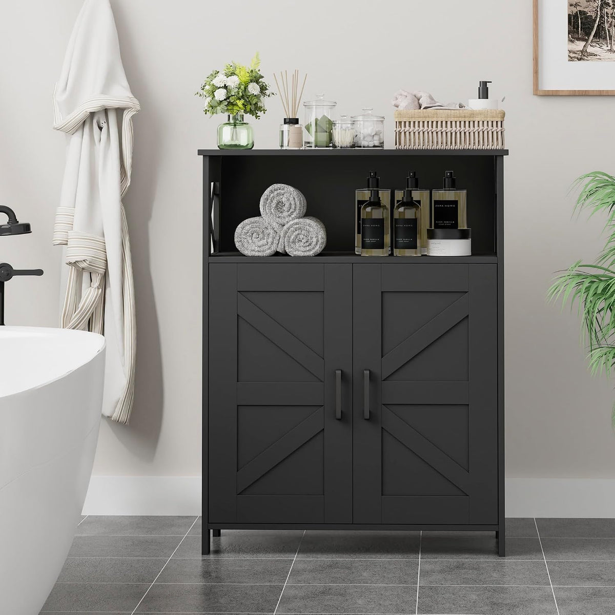 Black farmhouse bathroom cabinet front view in a bathroom setting with rolled towels on the open top shelf