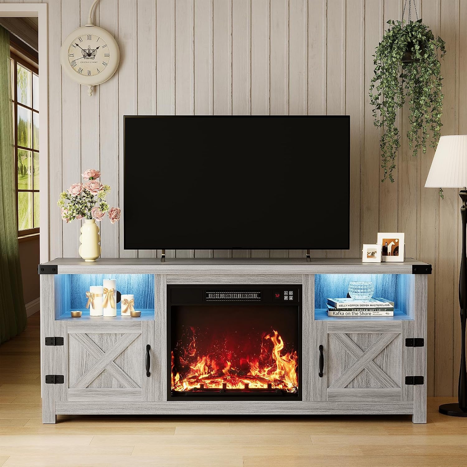 Light gray-washed media console with illuminated cubbies, electric fireplace insert and decorative items.