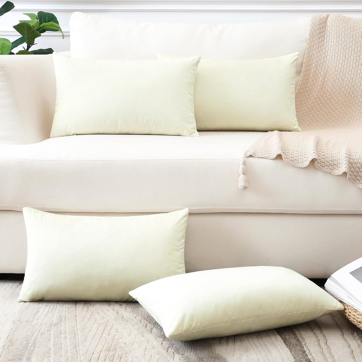 Two rectangular pale mint pillow covers on a cream sofa with two on the floor