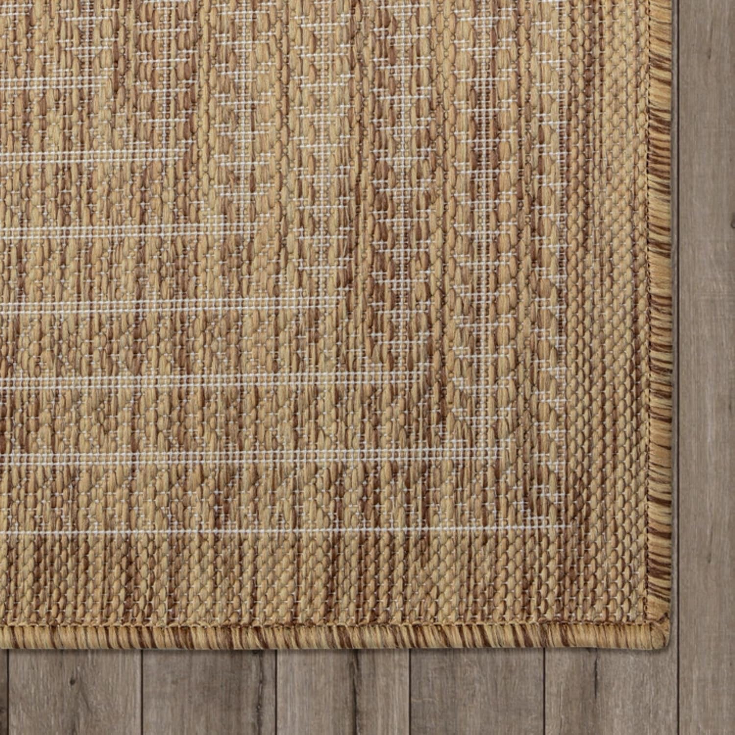 Top-down view of rug corner on wood floor showing stitched binding and woven pattern