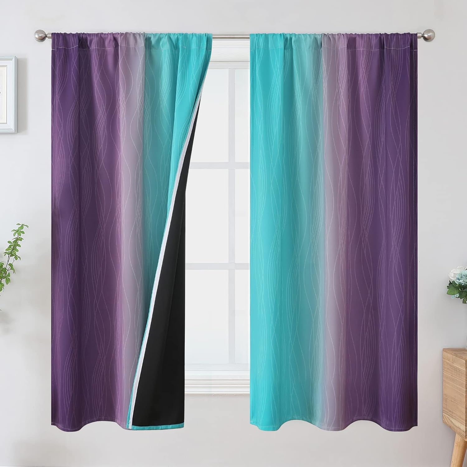 Two rod-pocket ombre curtains in teal and purple pulled aside to show black blackout lining.