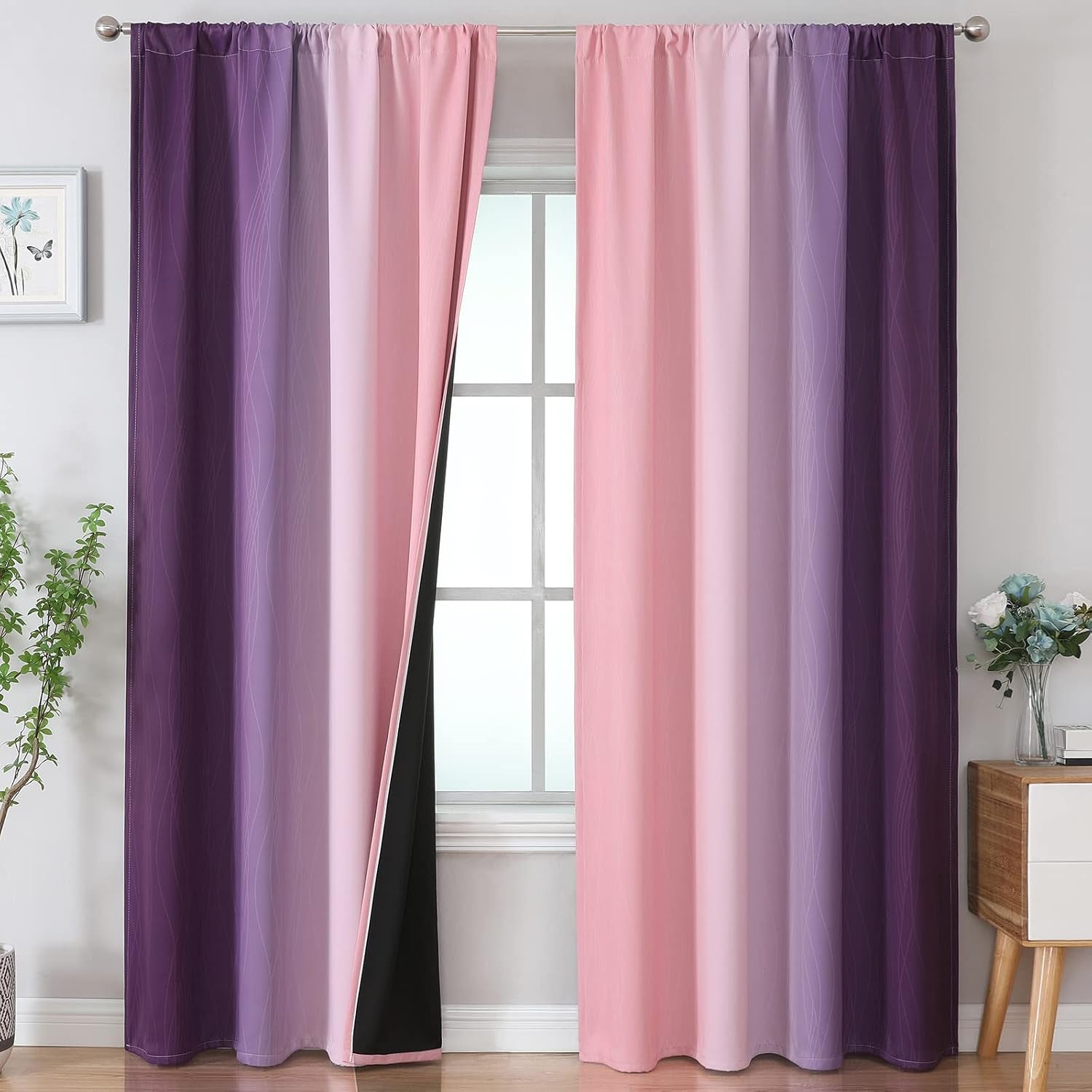 Pink-to-purple ombre curtains with black backing parted at center to show window, floor plant and bedside decor at sides.