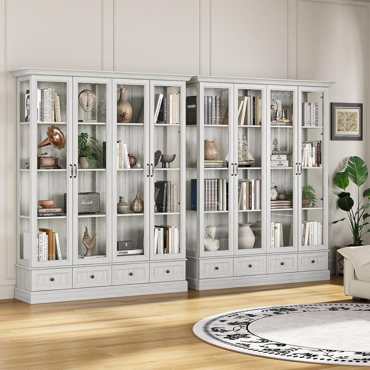 Two matching grey glass-front cabinets side by side in a living room with decorative items inside