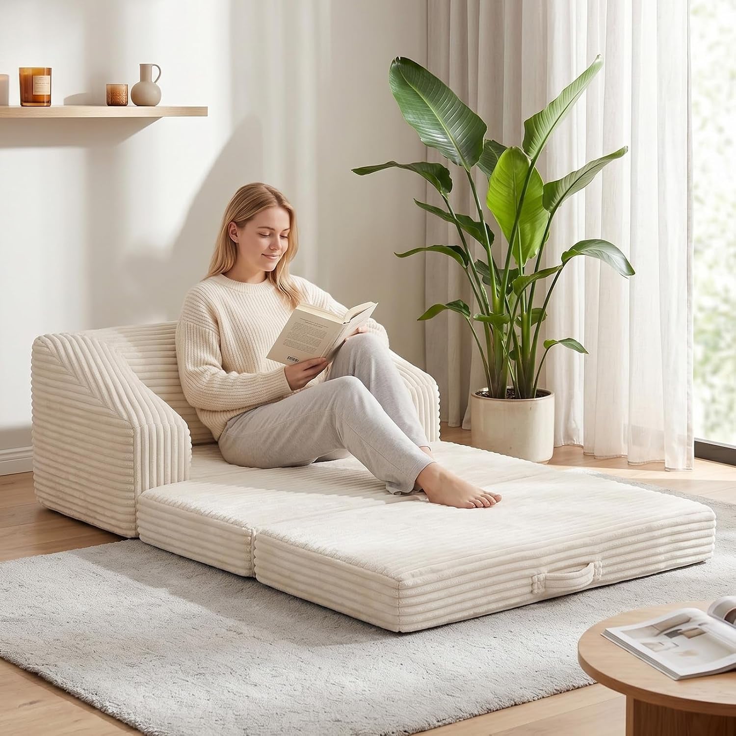 Woman sitting on the unfolded mattress leaning against the corduroy backrest in a neutral-toned room