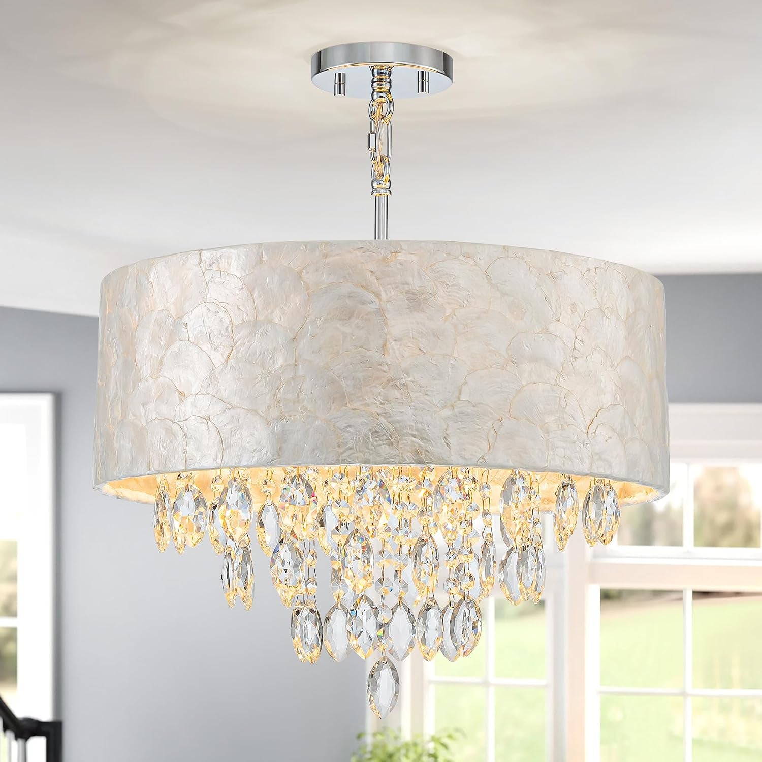 Interior view of the chandelier installed in a bright room showing the textured capiz shade and layered crystal drops from a
