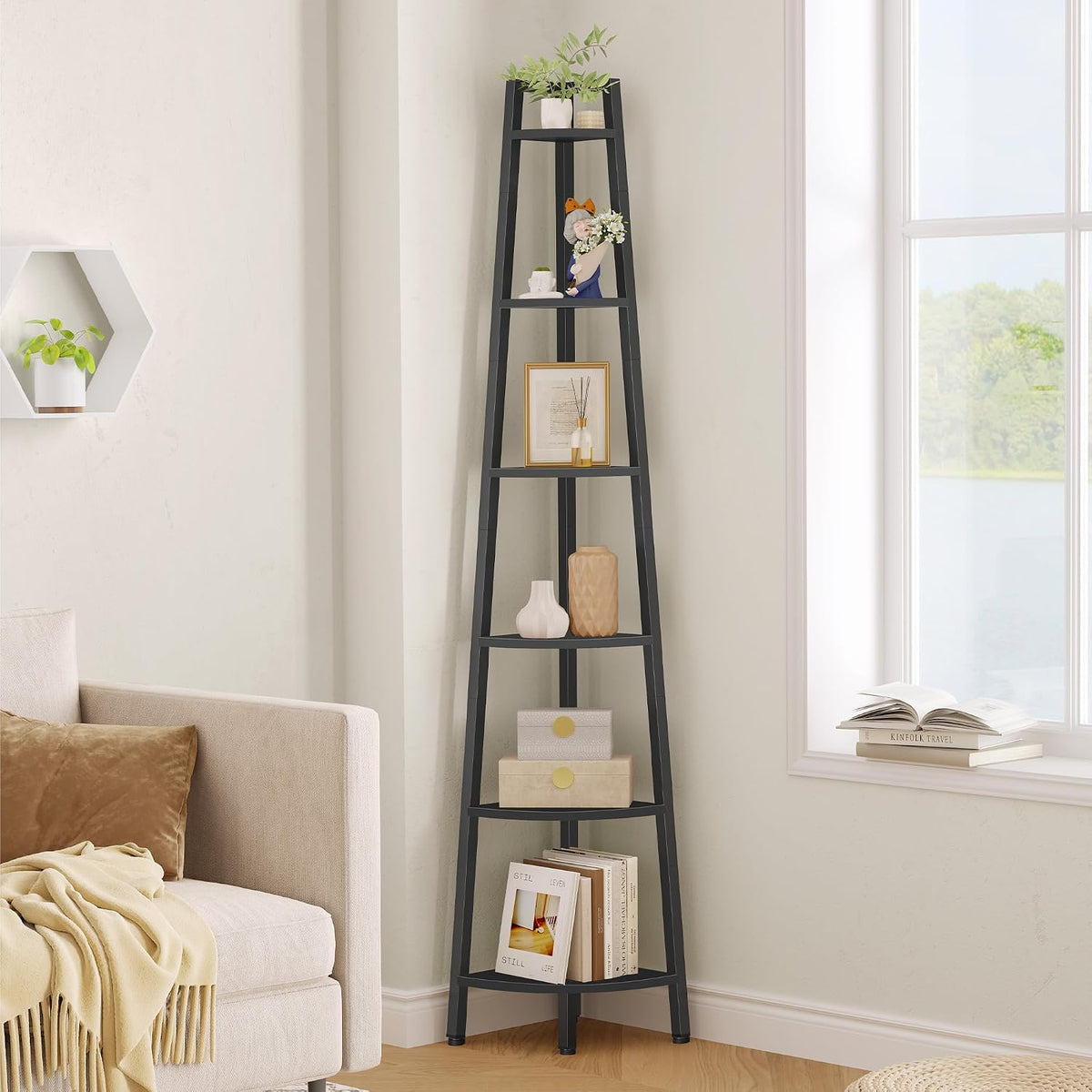 Tall black corner shelf staged beside a sofa with vases, a small plant and books on the shelves.