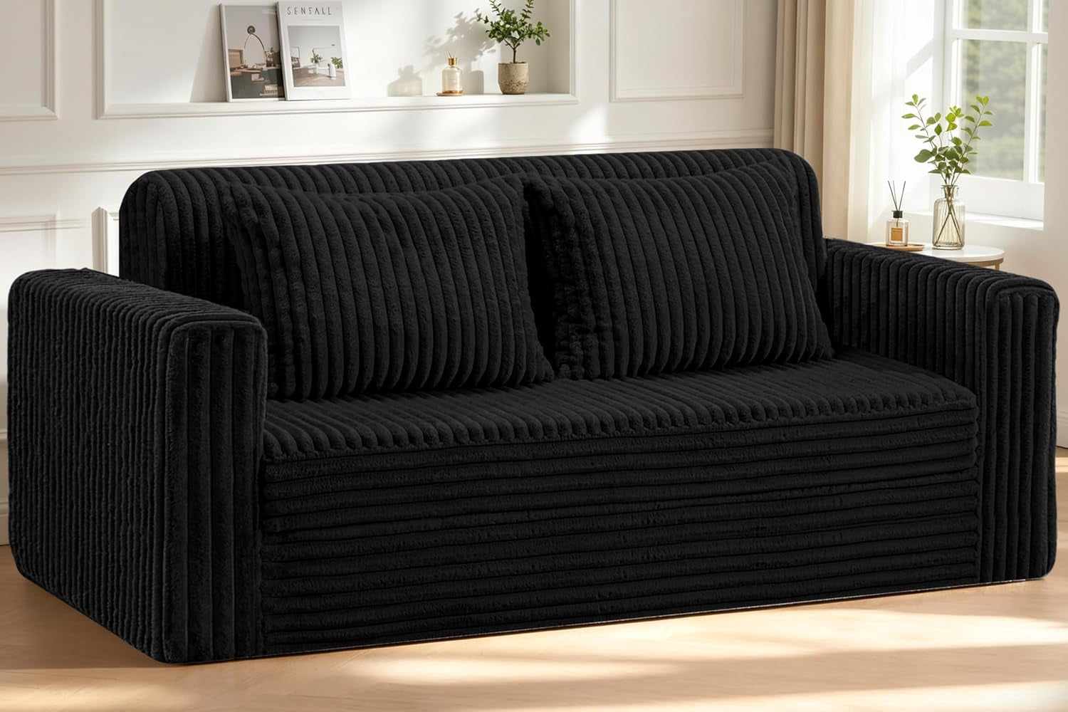 Front view of a black ribbed plush loveseat with two matching cushions in a sunlit room.