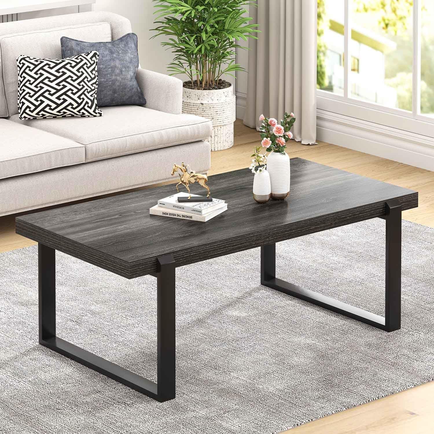 Living-room scene featuring the same coffee table in a dark charcoal wood-grain finish with vases on top.
