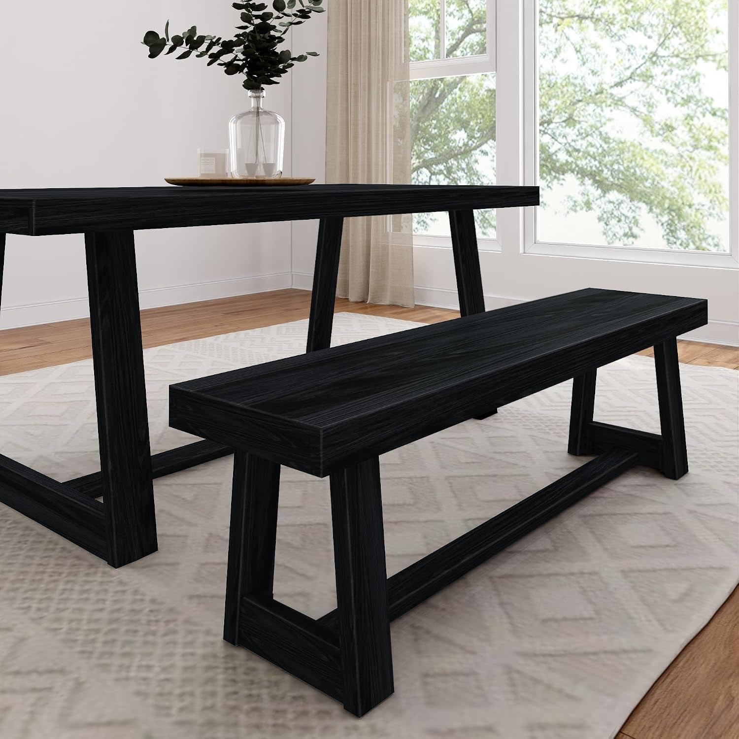 Angled close-up of a dining table and matching bench with trestle-style legs in a bright room.
