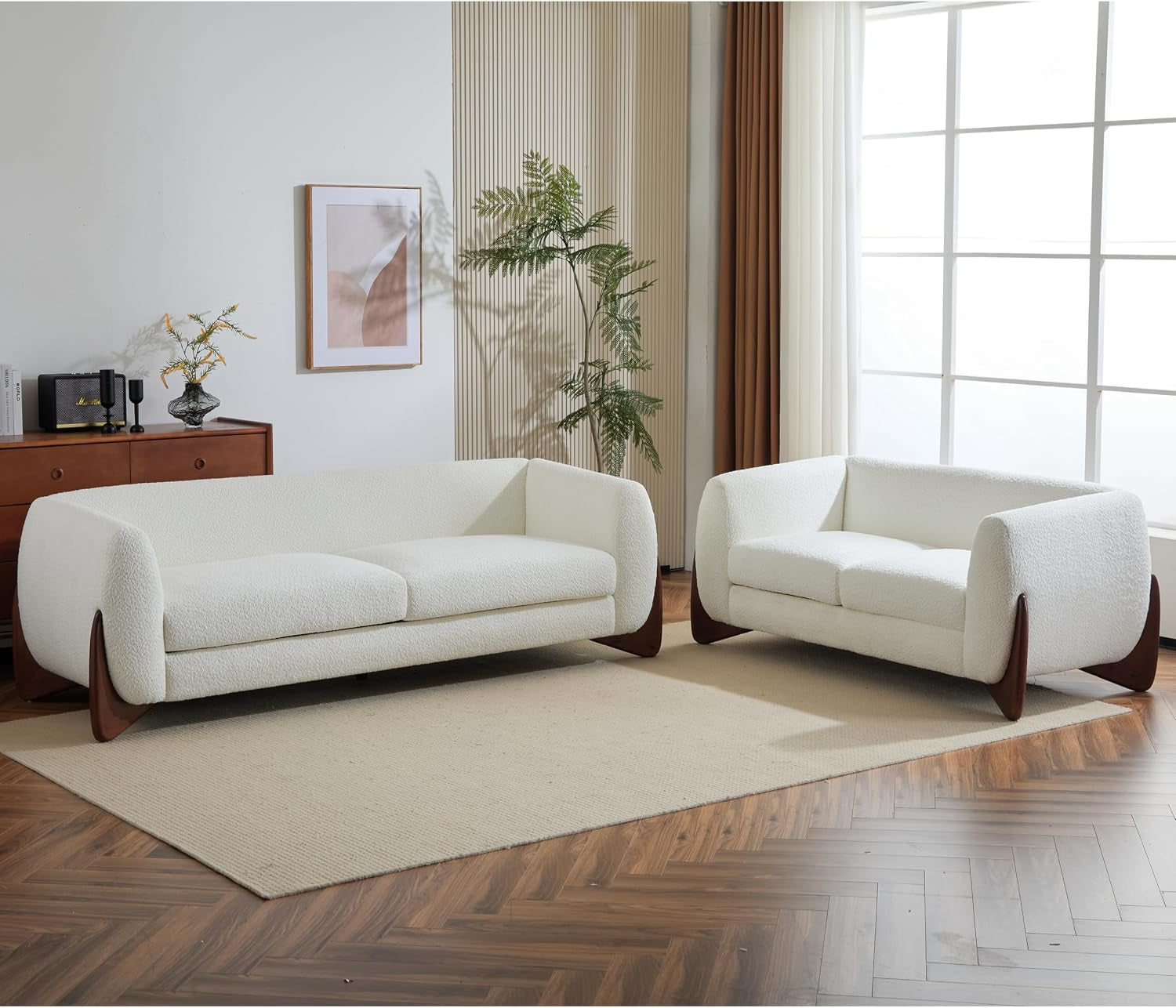 White bouclé three-seat sofa and matching loveseat angled front view with tapered natural wood legs in a staged living room