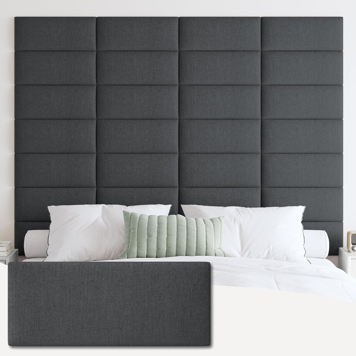 Tall grid of tufted rectangular panels in a deep charcoal fabric behind a bed with white pillows and a pale green lumbar