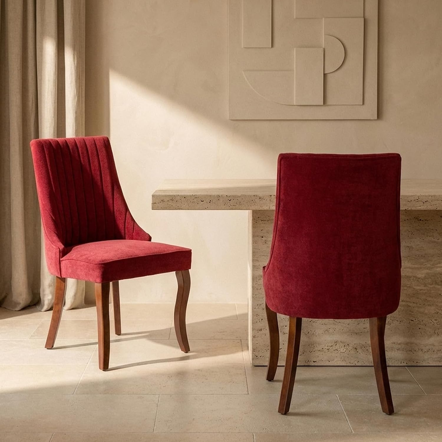 Two red upholstered dining chairs shown from side and rear next to a light stone table
