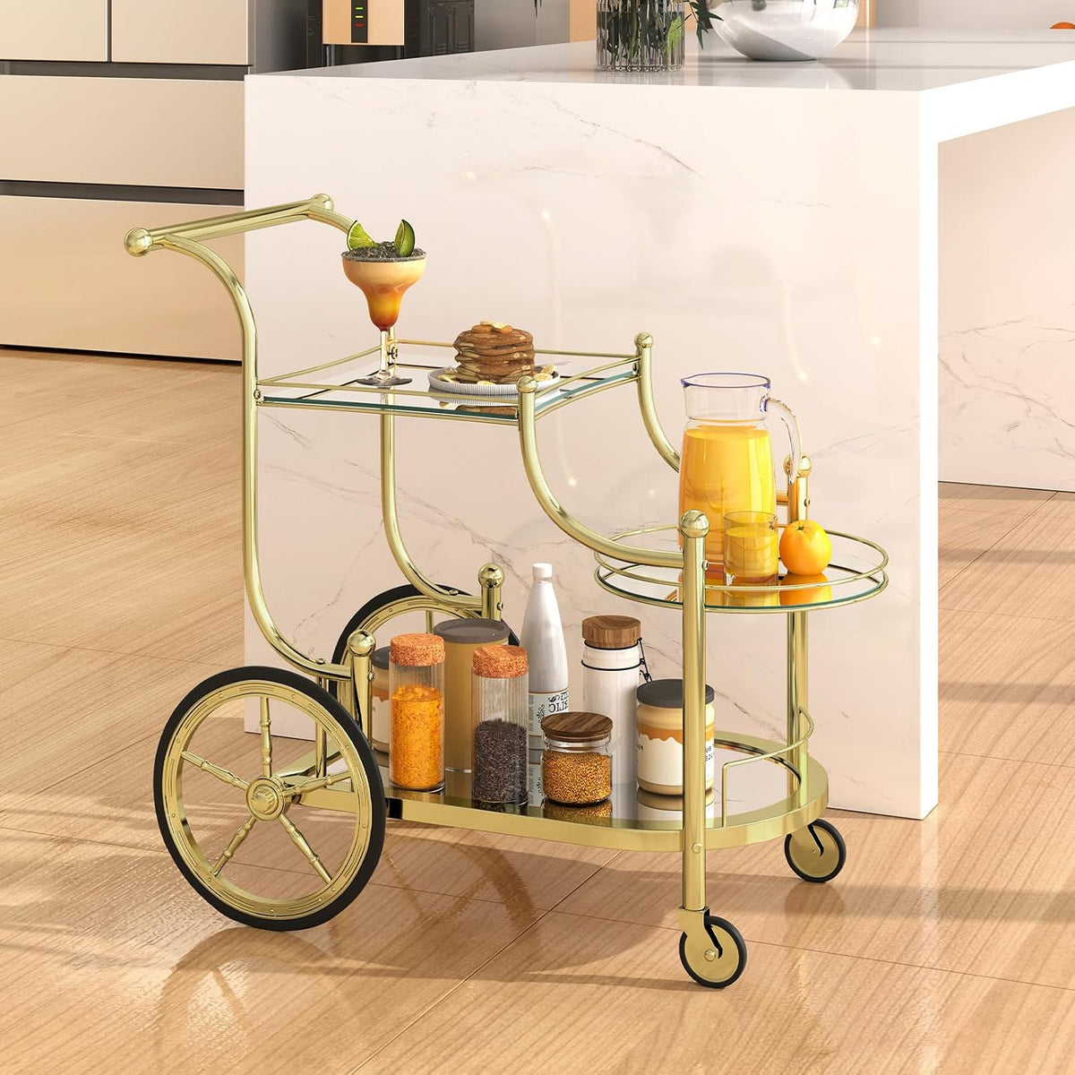 Gold rolling bar cart positioned beside a kitchen island holding jars, juice pitcher and plated snack