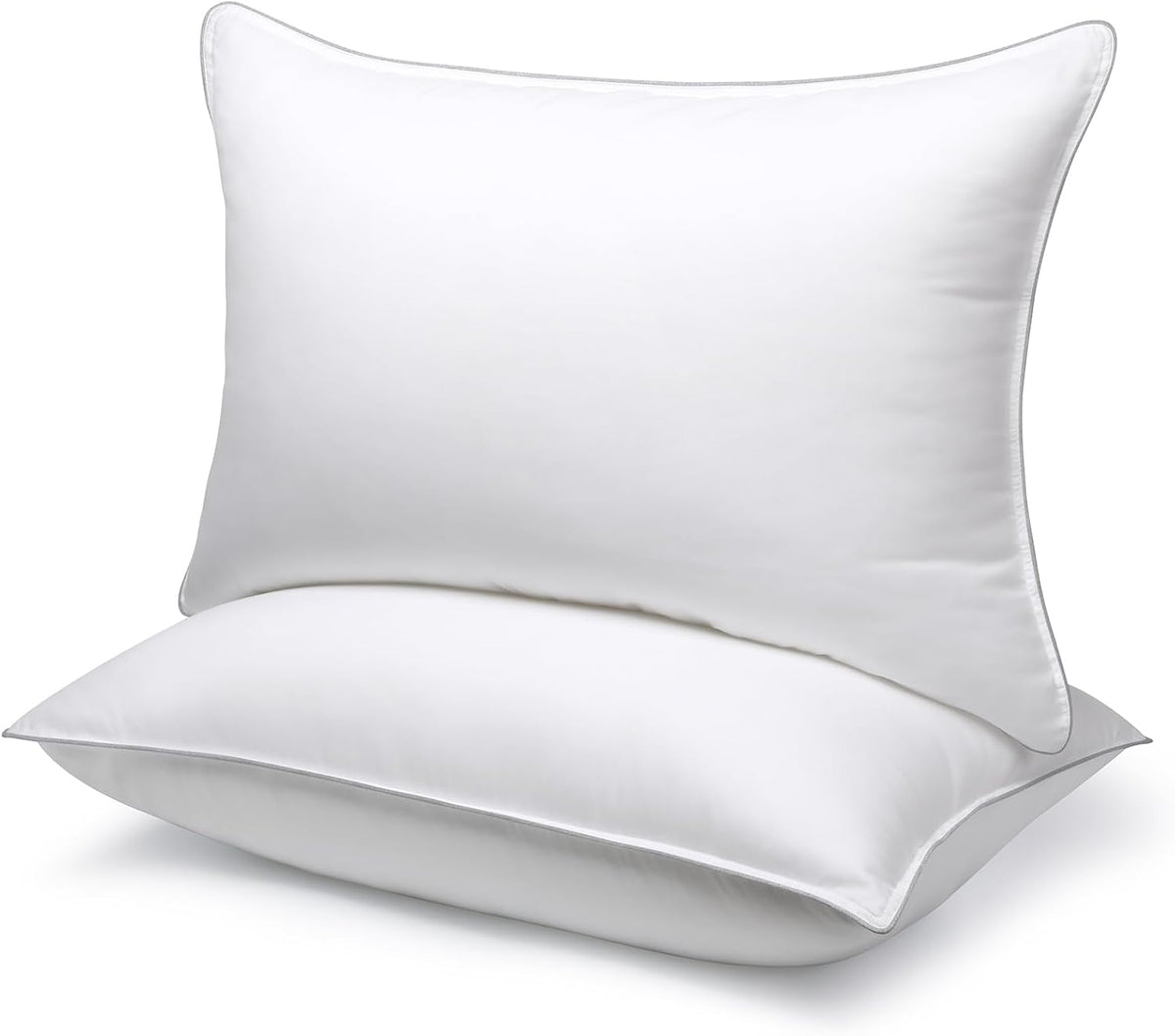Close-up front view of two white microfiber pillows on a plain background showing smooth cover and piped seams