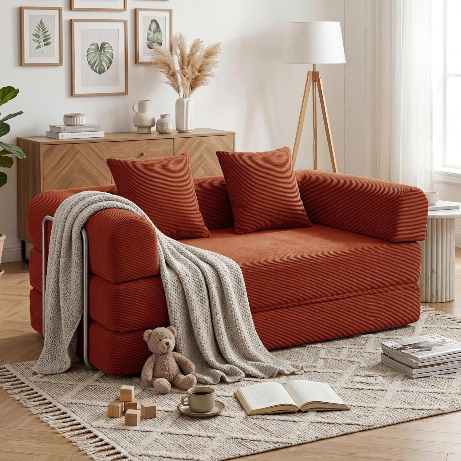 Rust-colored corduroy sofa in a cozy living room with a draped knit throw and toys on a patterned rug