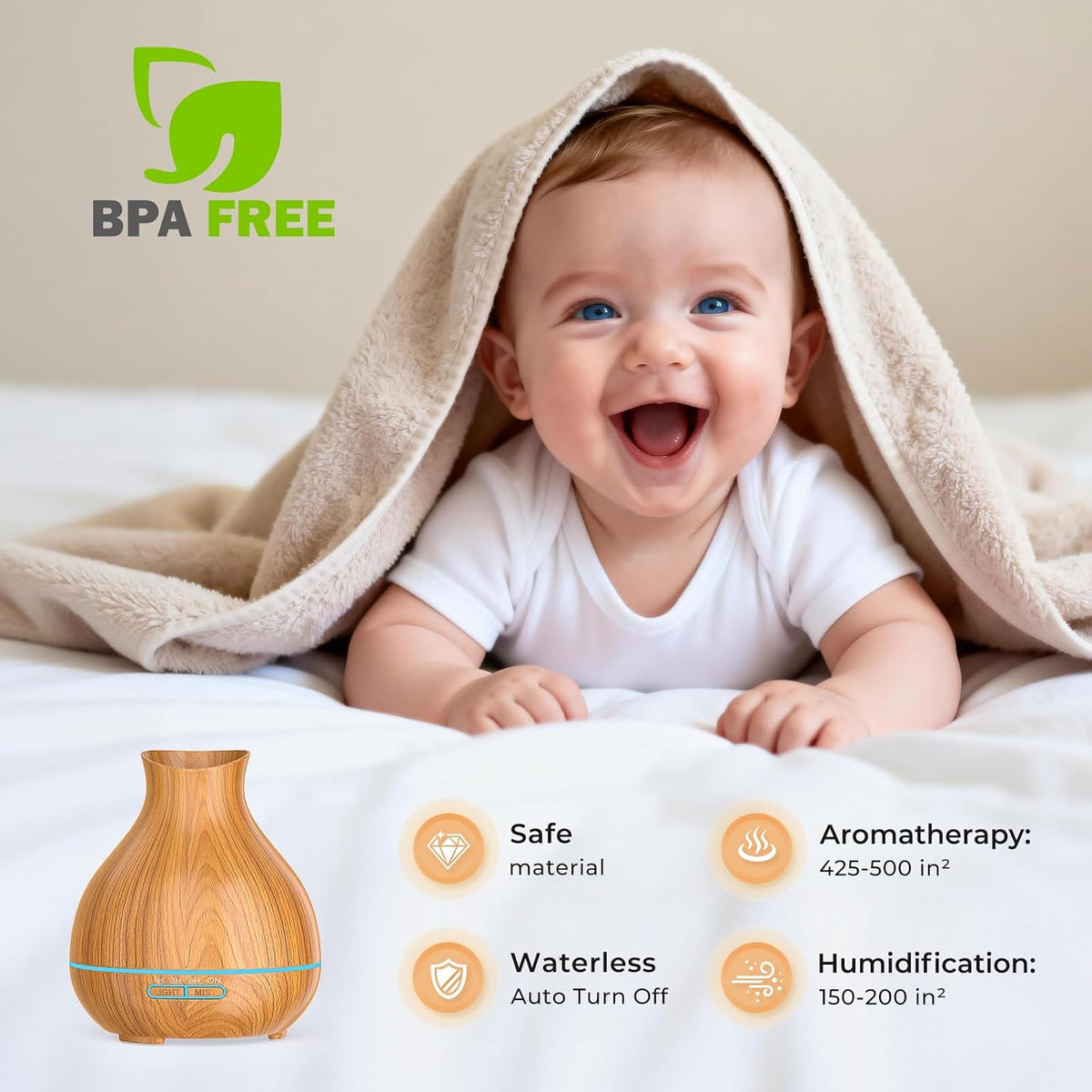 Smiling baby under a beige blanket on a bed with a wood-grain diffuser pictured at the bottom edge.