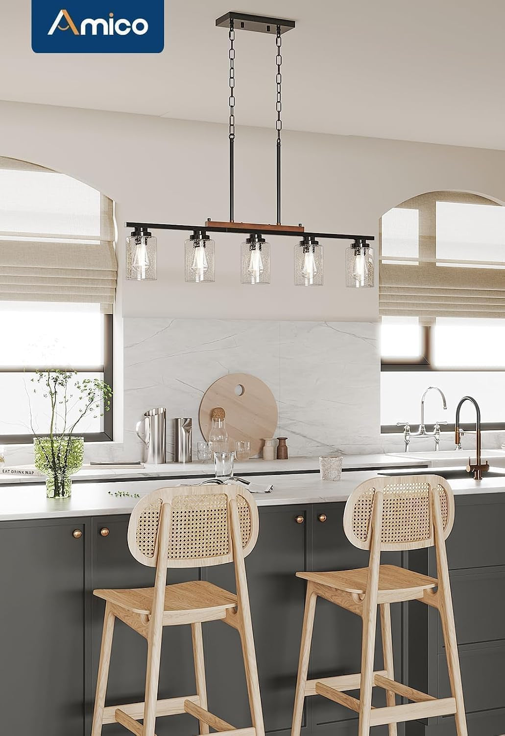 Five-light seeded glass pendant above a gray kitchen island with two light wood cane-back counter stools and stainless