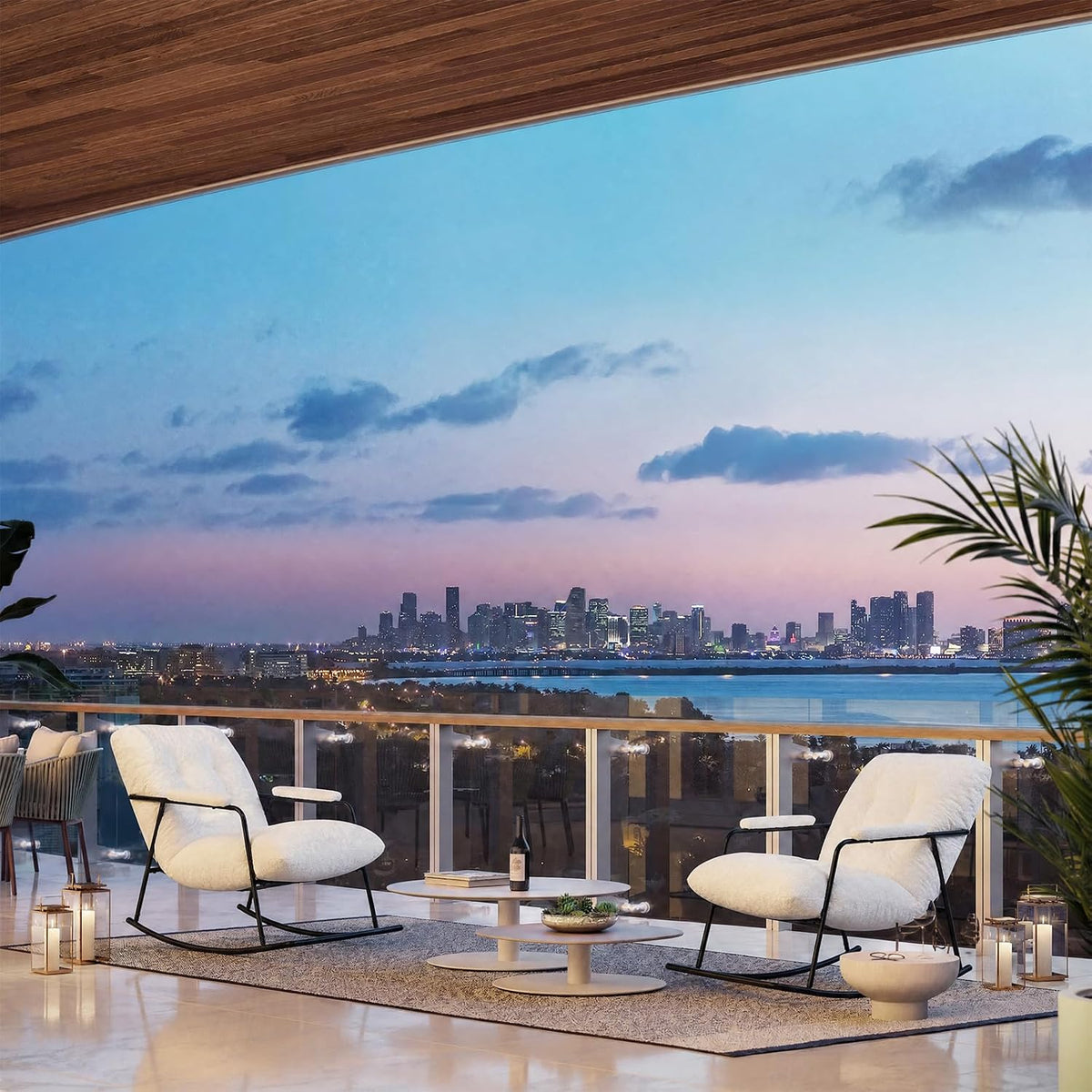Two white rocking chairs with black frames arranged around a low table on a balcony overlooking a city skyline at dusk.