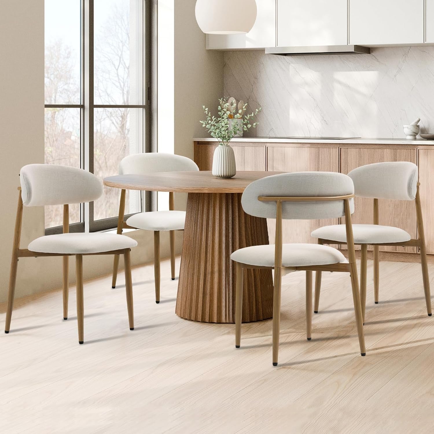 Beige upholstered dining chairs shown from rear and side around a round wood table in a kitchen setting