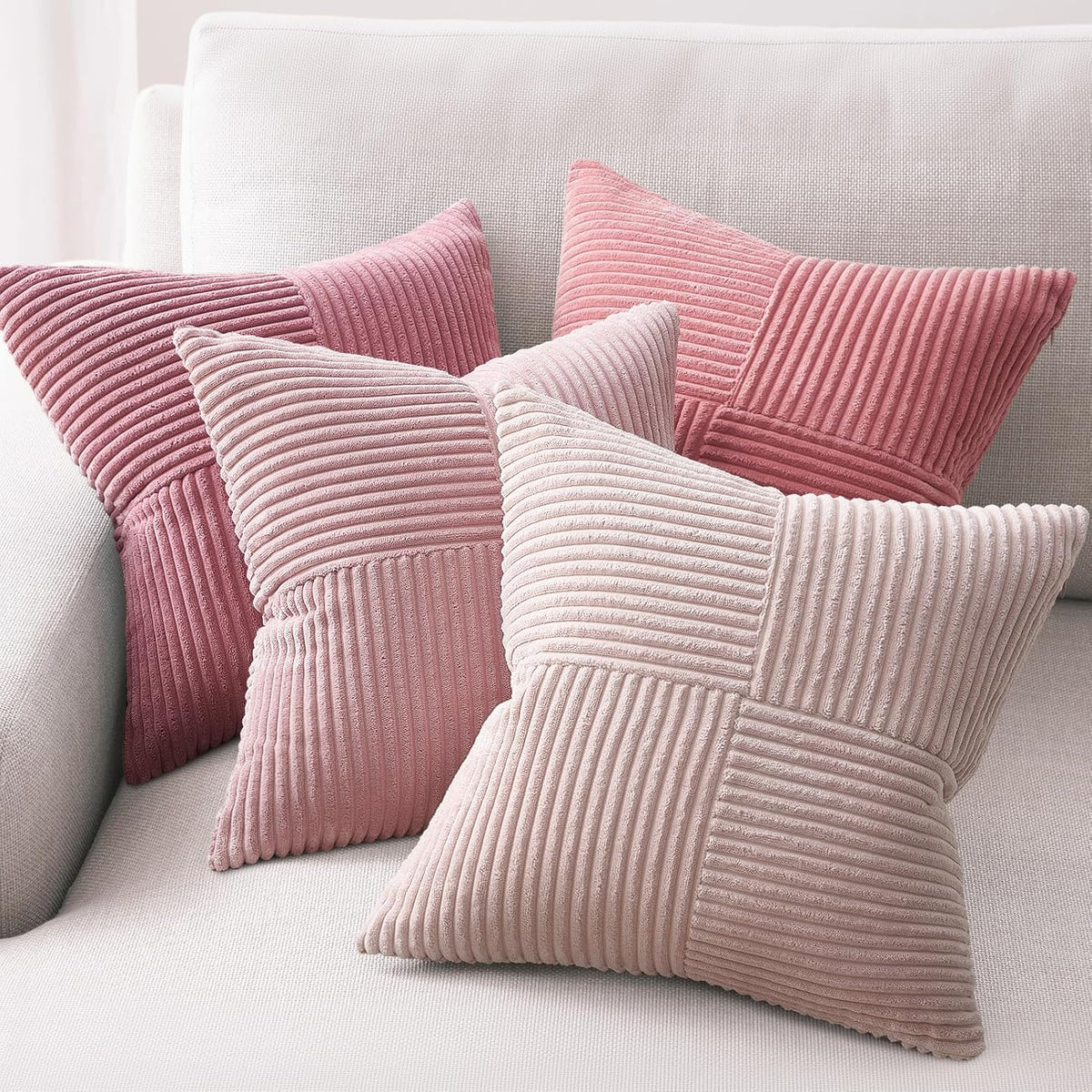 Set of four pink corduroy patchwork pillow covers styled on a pale sofa.