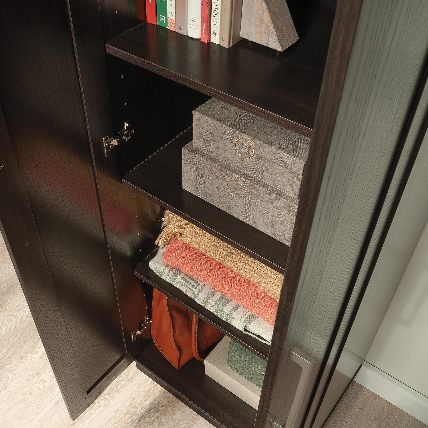 Interior close-up of cabinet showing adjustable shelf positions, folded linens, stored items, and door hinge hardware.