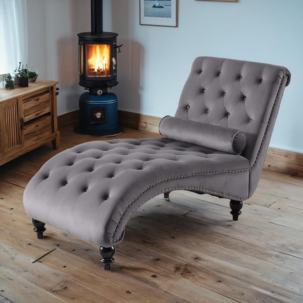 Grey velvet chaise lounge shown at an angle in a room with wood floors
