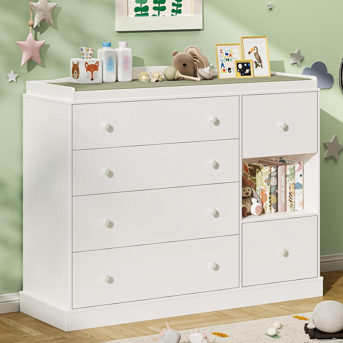 Angled view of the white dresser with changing pad on top and toys arranged on the open shelf.