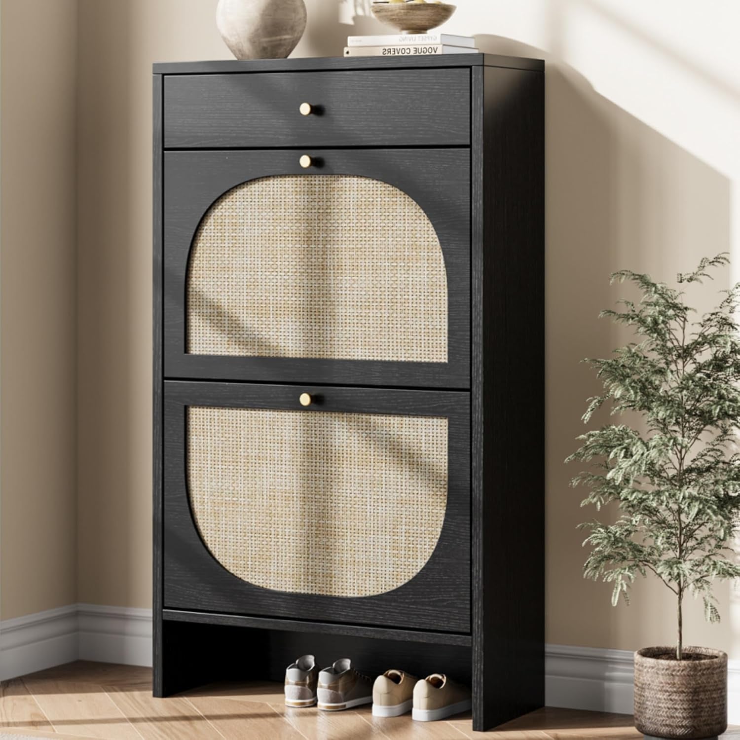 Angled view of a tall, narrow black shoe cabinet with two flip drawers, a small top drawer and shoes on the floor.