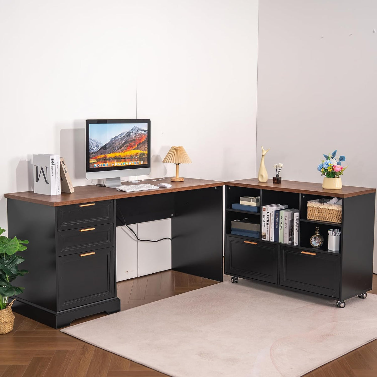 Black L-shaped desk with wood top, left drawer pedestal and right storage cabinet on wheels, staged with monitor.