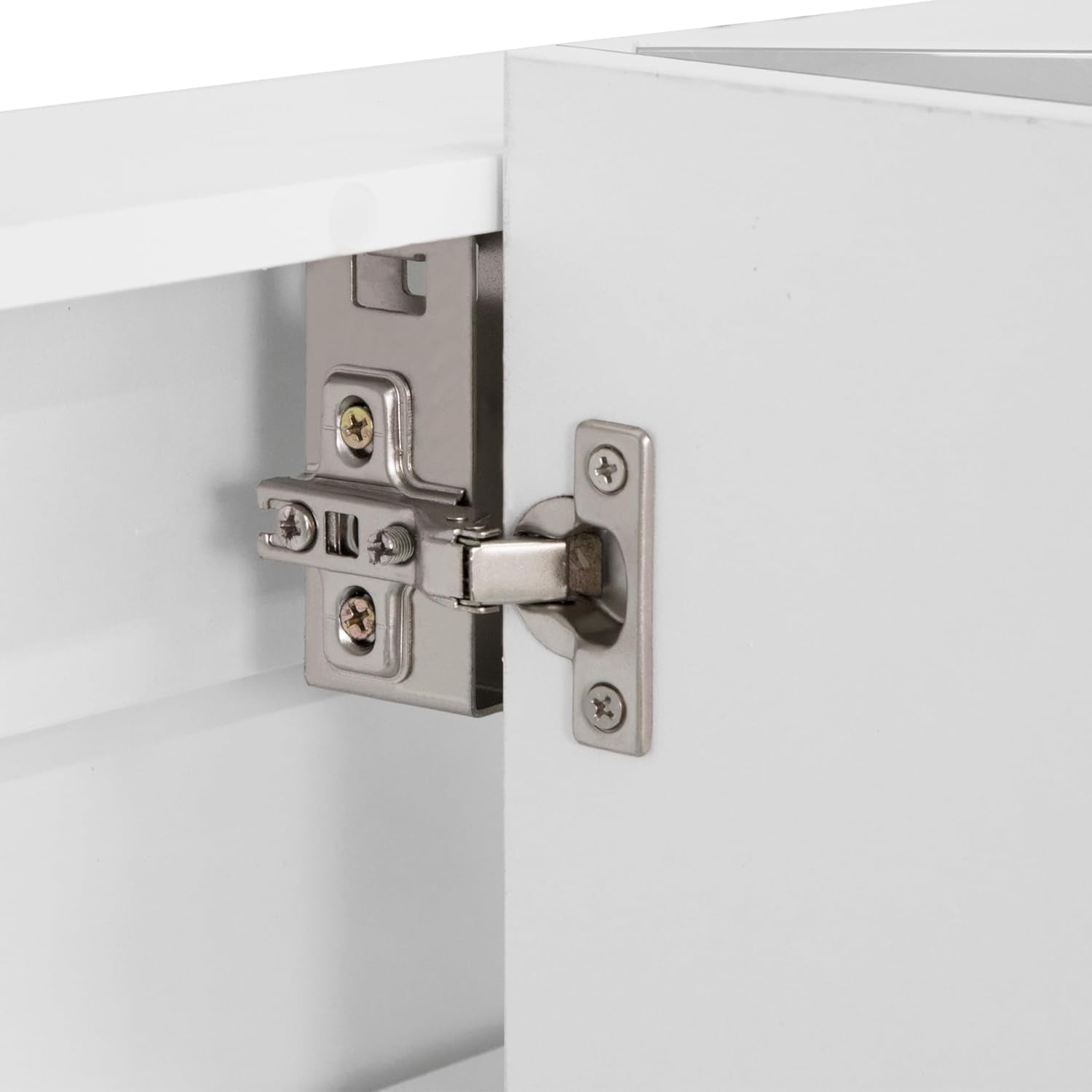 Close-up of a metal cabinet hinge attached to the inside edge of a white cabinet door
