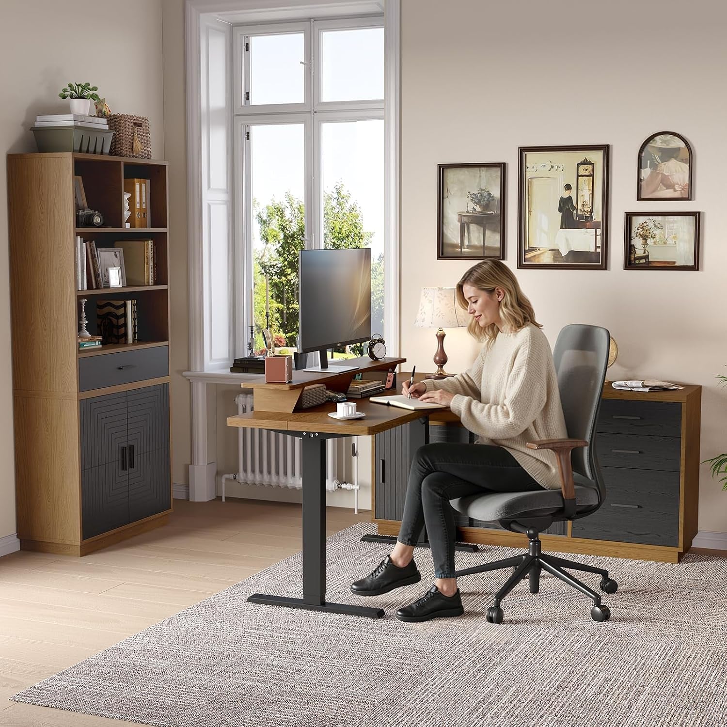 Woman seated at the height-adjustable desk writing, with matching bookcase and file cabinet arranged by a large window.