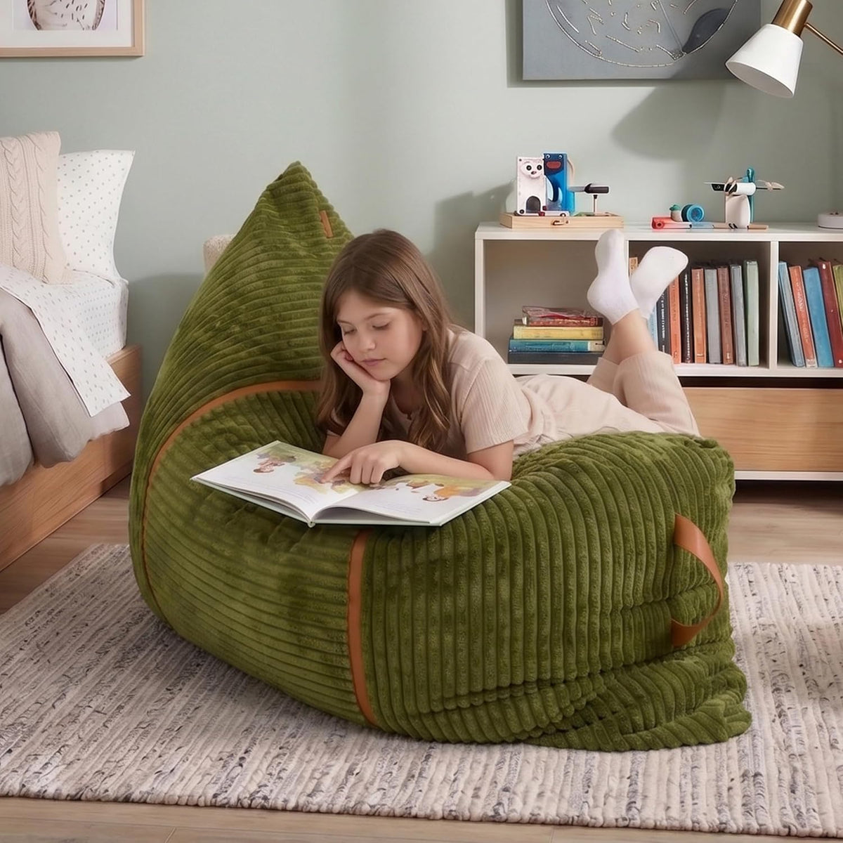 Girl reading a book while lying on a green corded bean bag in a bedroom