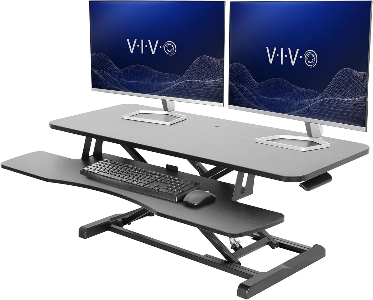 Black standing desk converter set up with dual monitors, keyboard tray and mouse on a white background