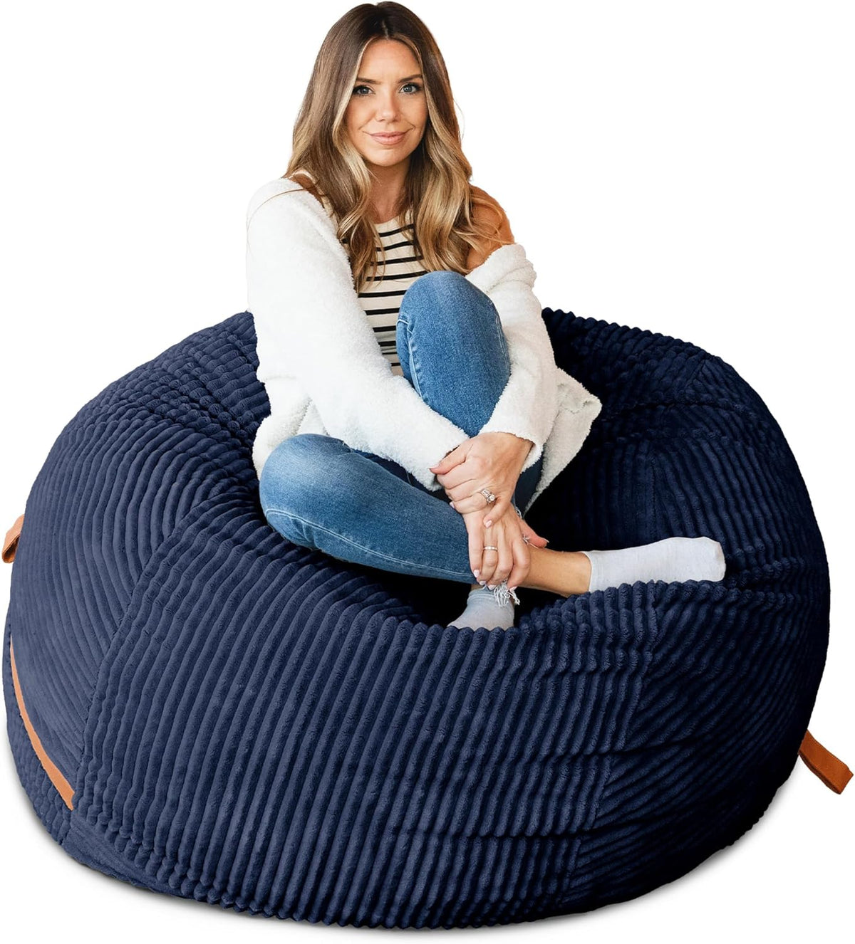 Woman seated cross-legged on a navy ribbed oversized lounger showing ribbed texture and a tan carry handle.