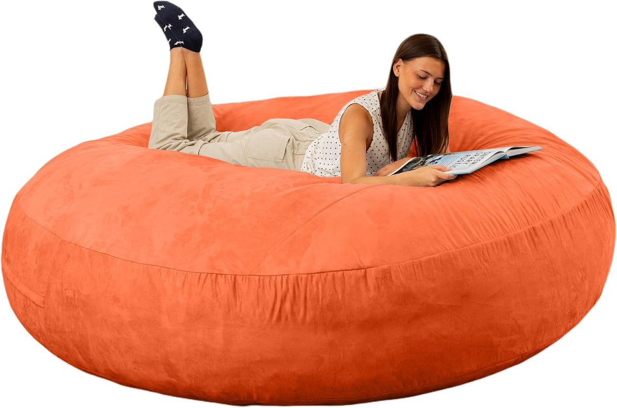 Woman lying on an oversized round orange bean bag reading a magazine on a white background